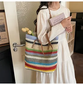 Detail of a colorful striped woven straw tote bag with brown leather shoulder straps