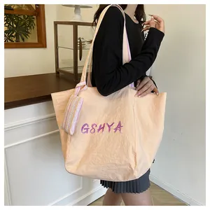 Detalle del bolso tote albaricoque con logo Gshya y cinta de rayas decorativa