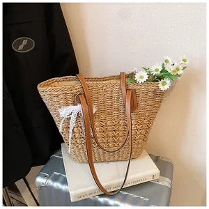 Detail of woven straw tote bag with brown leather straps and pearl bow ornament