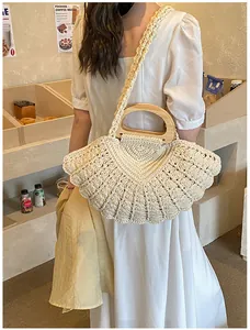 Close-up of fan-shaped beige woven handbag with semicircular wooden handles and strap