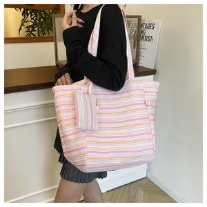 Detalle de bolso tote grande de lona a rayas con estuche con cremallera a juego al hombro