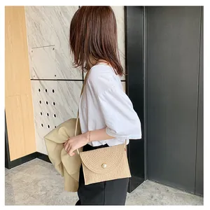 Détail du sac à bandoulière en paille beige avec un fermoir décoratif en perle