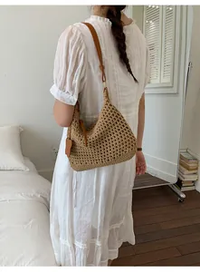 Detail of hand-woven straw tote bag with adjustable brown leather shoulder strap