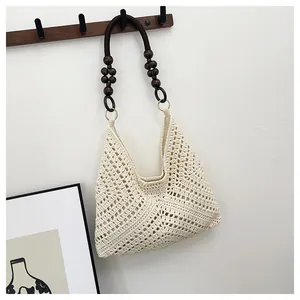 Detail of hollow woven beach bag with wooden beads on handles and bohemian style
