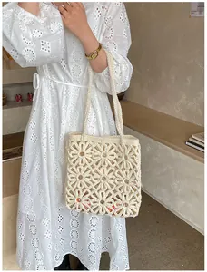 Detail of hand-woven daisy hollow pattern on beige tote bag with intricate knit texture