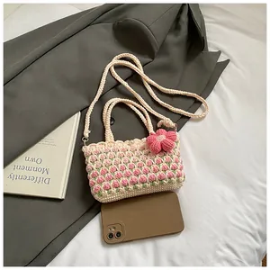 Detail of handmade crochet crossbody bag with pink tulip patterns and floral charm