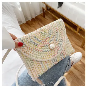 Détail du sac en paille avec broderie arc-en-ciel et boucle en perle centrale