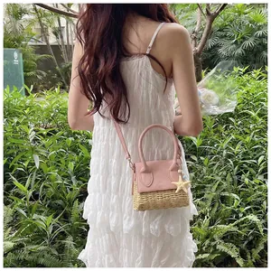 Outdoor shot of a pink straw bag with starfish charm held by a woman in a lace dress