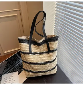Detail shot of the textured woven rainbow stripes and black leather straps on a tote bag