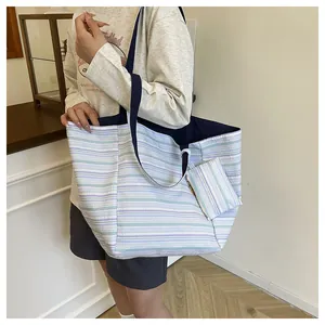 Detalle de un bolso tote grande a rayas con neceser a juego en el hombro de una modelo