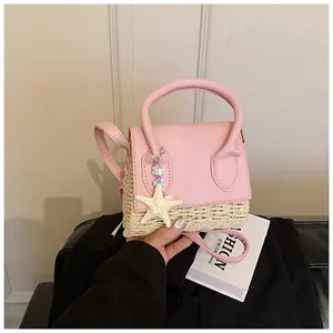 Detail of pink leather and straw woven handbag with starfish charm for summer