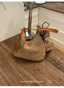 Detail of hand-woven beige tote with brown faux leather strap and flower charm on wood