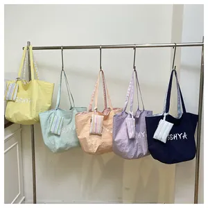 Fila de bolsos tote coloridos en nailon con estuches de rayas colgados en soporte