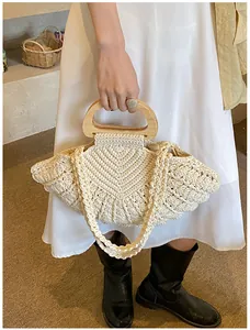 Detail of hand-woven cotton fan-shaped bag with wooden handles and floral ball texture