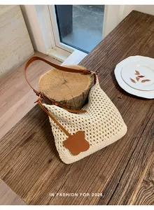 Detail of hand-woven cream tote with brown leather strap on rustic wood background