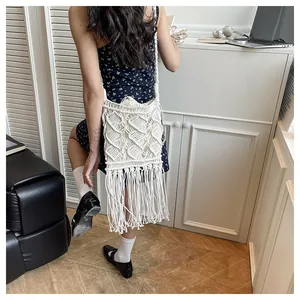 Detail of white macramé woven shoulder bag with long fringe and diamond texture