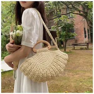 Detail of woven shell-textured shoulder bag with natural wooden handles and cotton strap