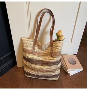 Detail of hand-woven straw tote with rainbow stripes and leather handle stitching