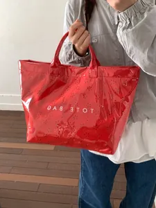 Glossy red waterproof tote bag with black dot pattern and bold TOTE BAG lettering