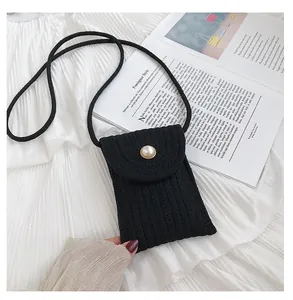 Détail d'un petit sac bandoulière noir matelassé avec boucle en perle sur tissu plissé
