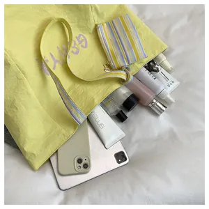 Vista detallada del bolso tote amarillo con asa de rayas de colores y monedero a juego
