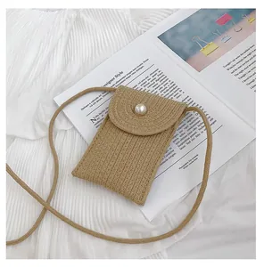 Détail d'un petit sac tissé avec un bouton perle décoratif et une fine bandoulière