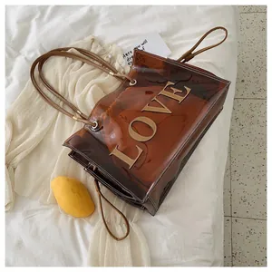 Detail view of transparent brown PVC tote bag with LOVE patch and drawstring inner pouch