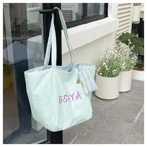 Detalle de bolso tote verde claro con estampado GSHYA, estuche pequeño y dije de conejo