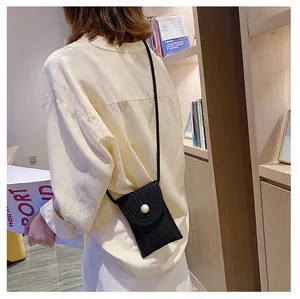 Détail d'un petit sac à bandoulière en tricot noir avec perle et texture rayée