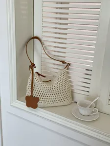 Minimalist woven tote bag in cream white with brown shoulder strap and butterfly charm