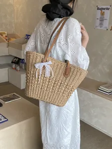 Large straw tote bag with brown leather straps and lace pearl bow charm for beach vacation