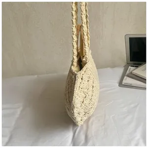 Detail of hand-woven cream cotton bag with wooden handle and long shoulder strap