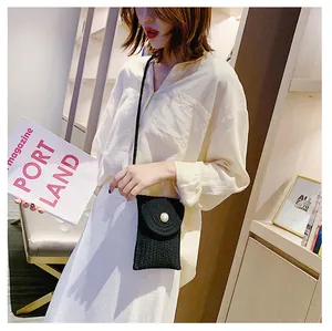 Détail d'un sac bandoulière tissé noir avec une perle sur le devant porté par un mannequin