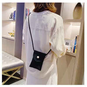 Détail d'un mini sac bandoulière tissé noir avec une fermeture à bouton perle élégante
