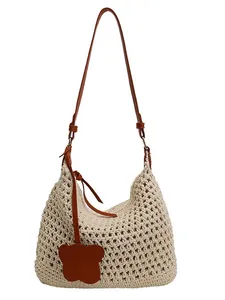 Handwoven beige mesh shoulder bag with brown leather straps and butterfly charm