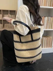 Rainbow striped straw tote bag with black leather straps shown against a bookshelf