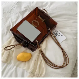 Detailed shot of a brown transparent tote bag with drawstring inner pouch and LO emblem