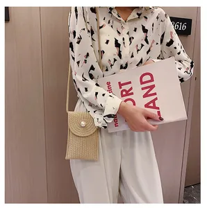 Détail du mini sac de téléphone en paille tressée beige avec décoration de perle blanche