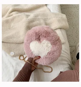 Detail of pink plush heart round bag featuring soft faux fur texture and gold chain strap