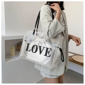 Detail of transparent PVC tote bag featuring black LOVE letters and canvas inner pouch