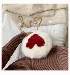 Detail of soft white plush round bag with red heart pattern and golden chain strap