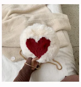 Detail of white plush round bag with red heart pattern and gold chain strap