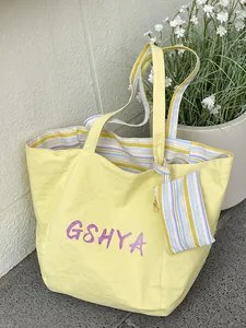 Bolso tote grande amarillo con texto GSHYA y neceser interior de rayas a juego