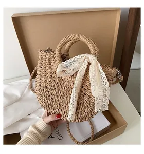 Detail of semi-circular straw bag with round handle, lace bow, and adjustable strap