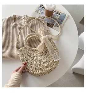 Close-up of semi-circle straw bag with delicate lace bow and woven shoulder strap