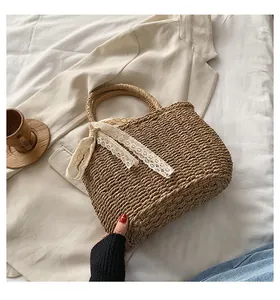 Detail of straw tote bag featuring natural weave texture and elegant white lace ribbon handle