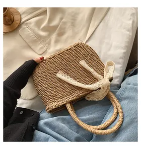 Detail of hand-woven straw tote with elegant lace bow decoration and round handles
