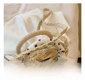 Detail of beige straw handbag with geometric silk scarf handle and drawstring lining