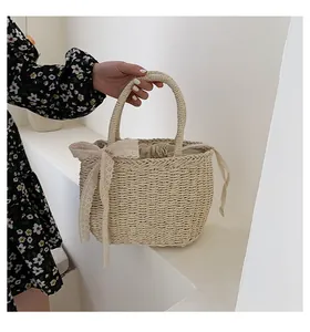 Detailed texture of hand-woven straw beach bag with cream lace bow and drawstring liner