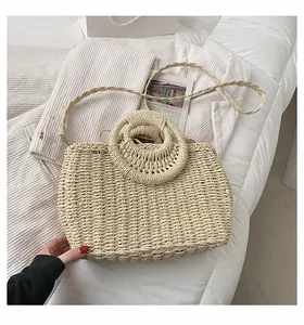Dettaglio della borsa in paglia intrecciata beige con manici tondi e trama fine